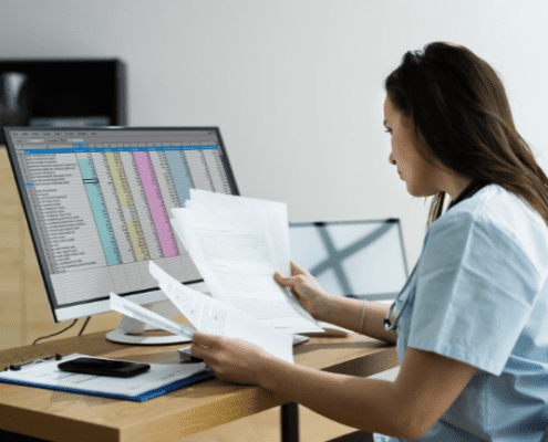 Woman sitting at desk looking at excel sheet whole reviewing documents