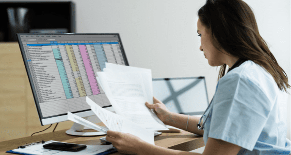 Woman sitting at desk looking at excel sheet whole reviewing documents