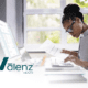 woman crunching numbers on calculator in front of computer while holding documents - Valenz Health