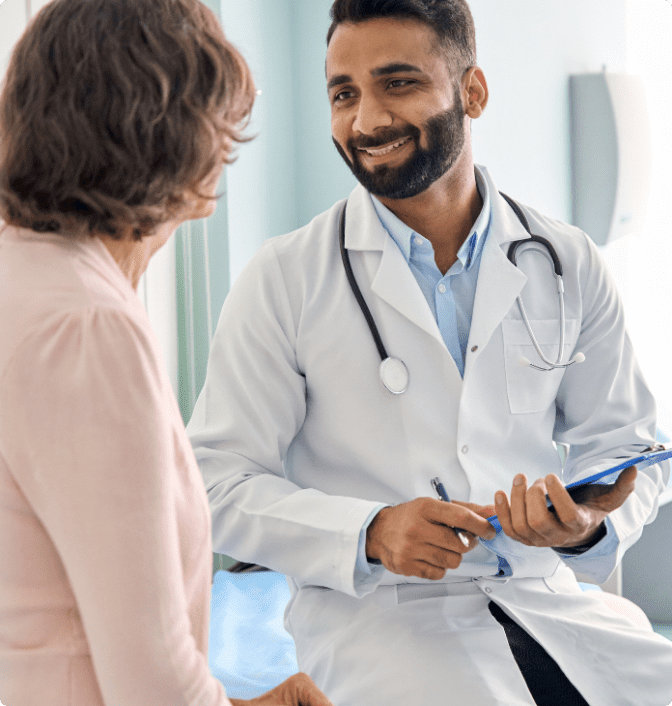 A male doctor talks to a female patient at an appointment.