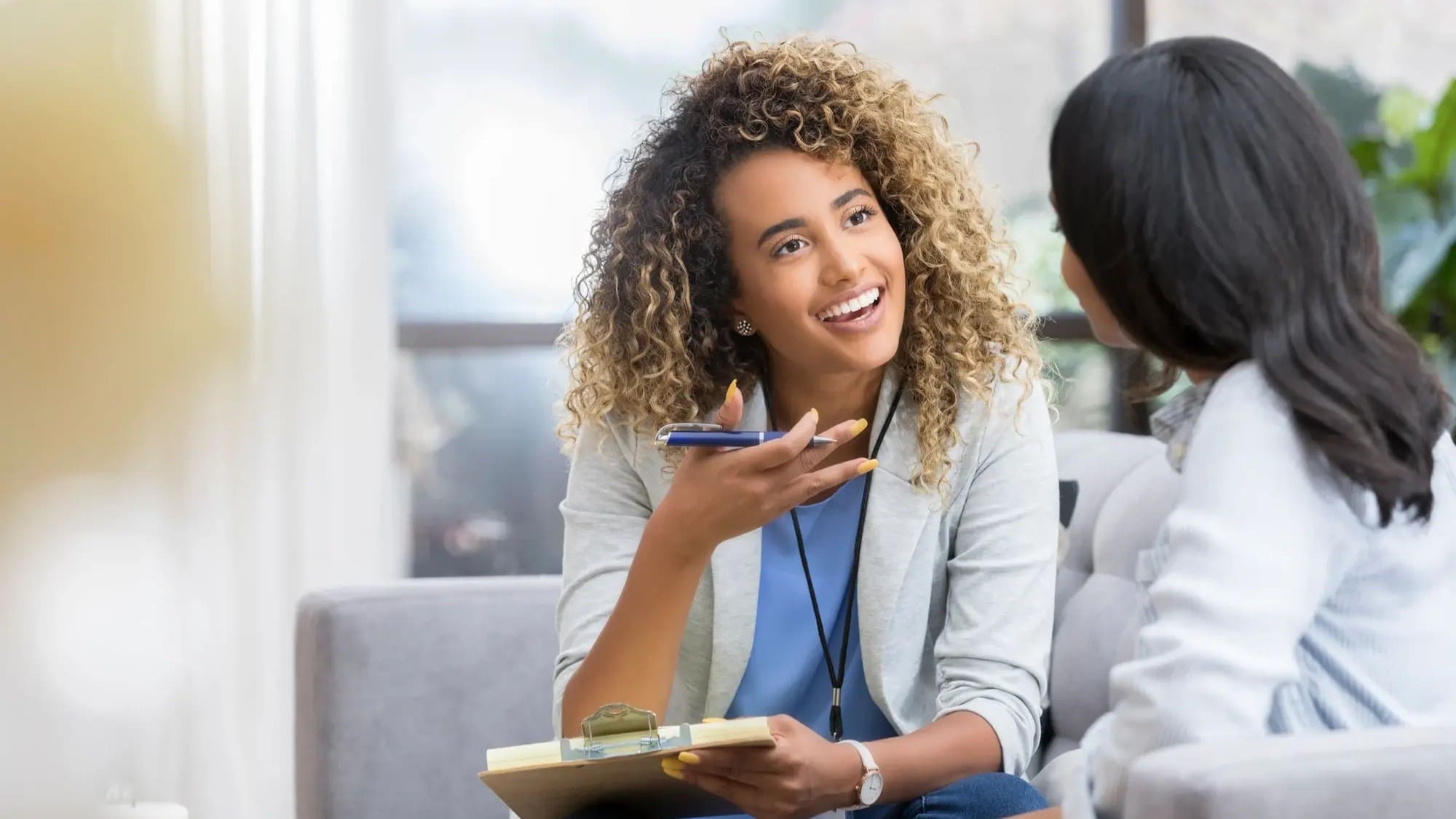 Two women discuss compliance procedures while sitting in an office.